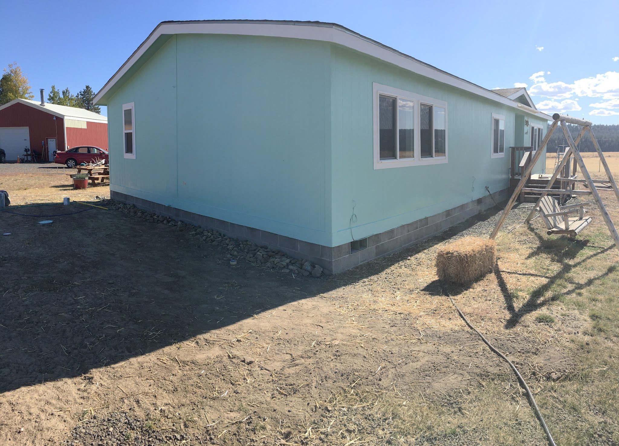 Manufactured home repainted soft mint green with fresh white trim under a blue sky