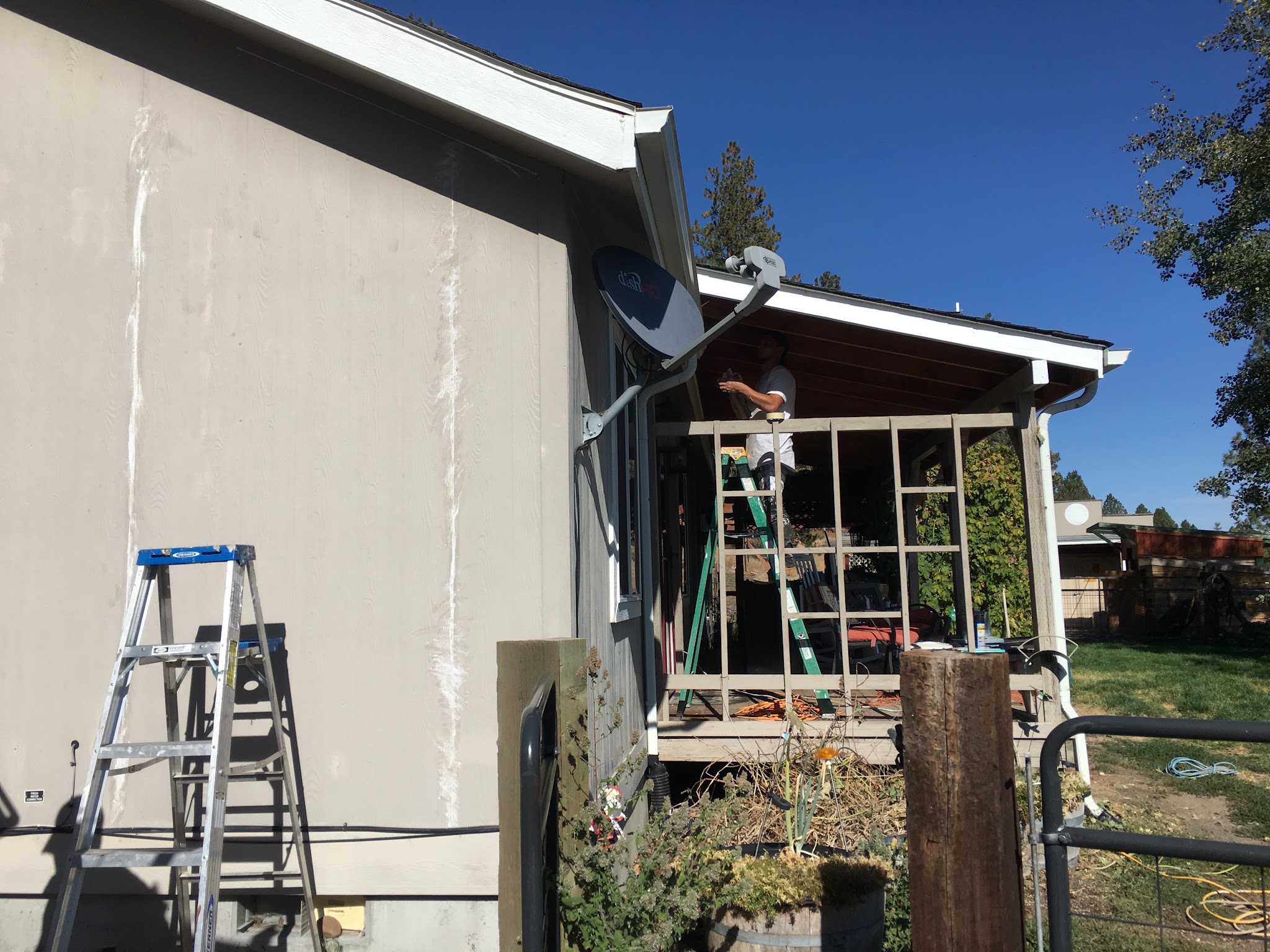 Crew member on a ladder working on a porch soffit